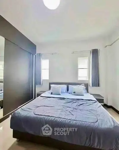 Spacious bedroom with modern decor and ample natural light, perfect for relaxation.