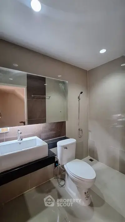 Modern bathroom with sleek fixtures and spacious design, featuring a large mirror and elegant lighting.