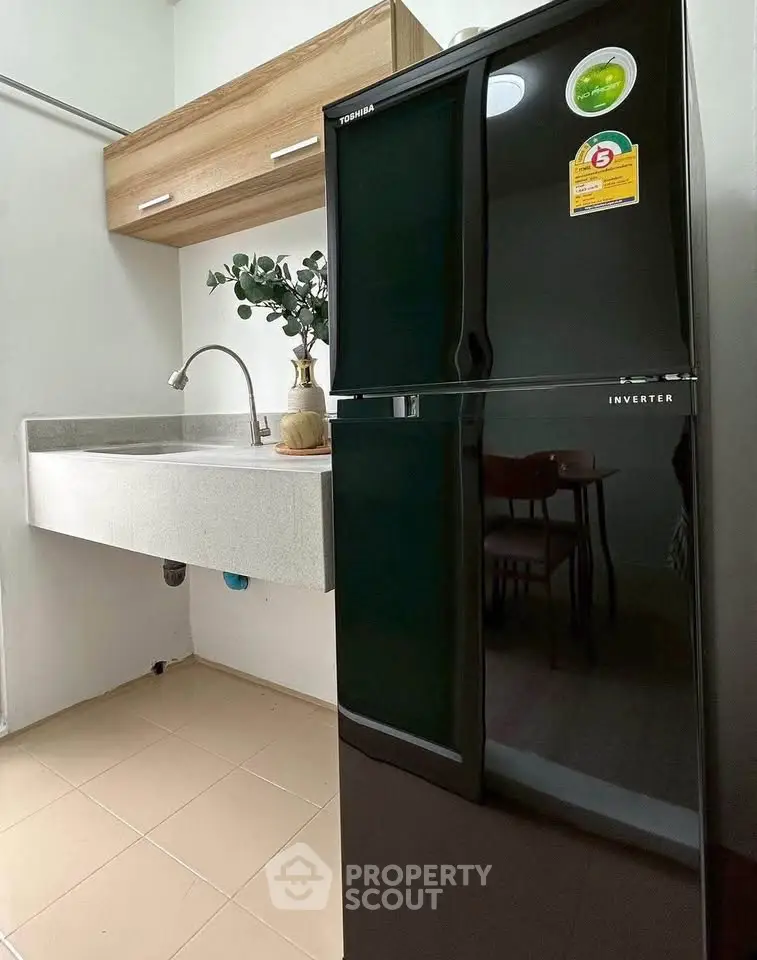 Modern kitchen with sleek black refrigerator and stylish sink area.