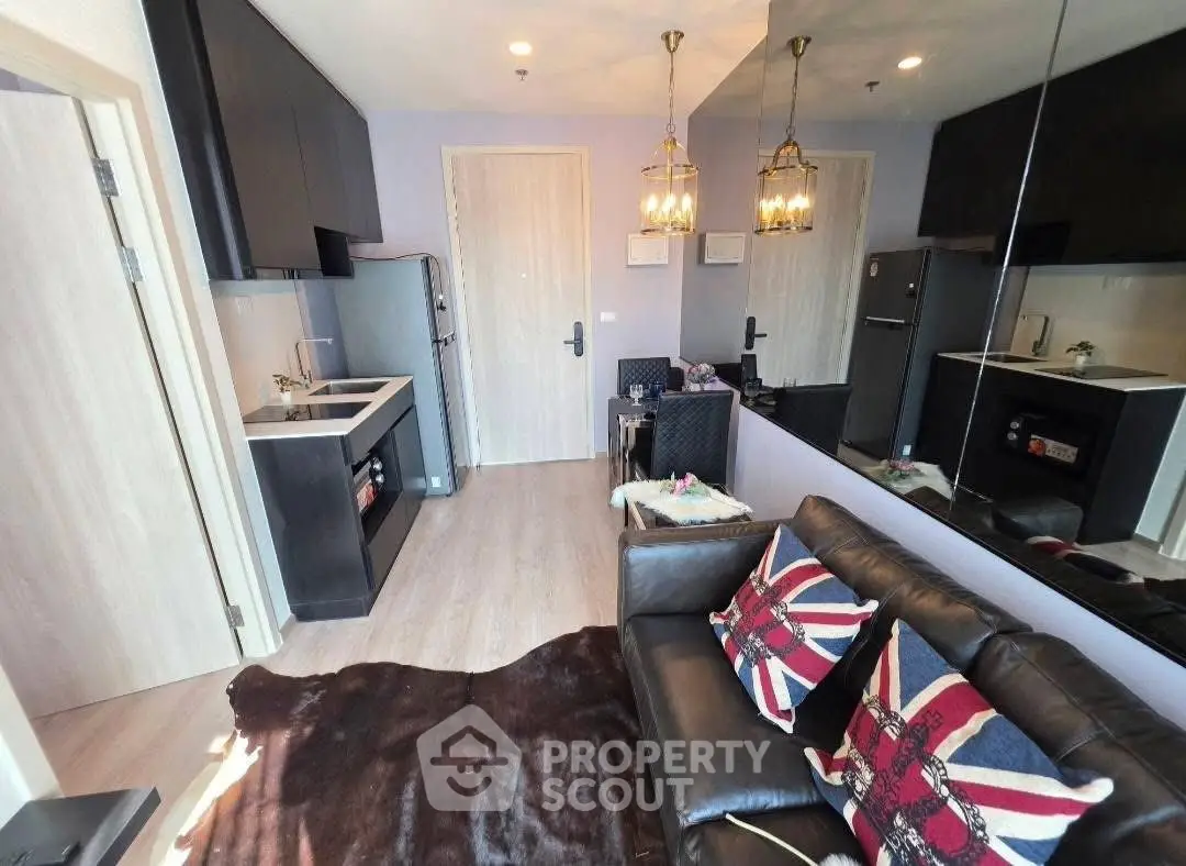 Modern living room with stylish decor and open kitchen layout, featuring a cozy sofa and elegant lighting.