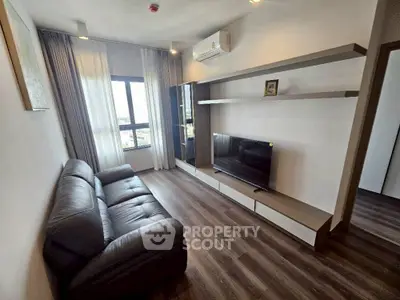Modern living room with sleek furniture and large window offering natural light.