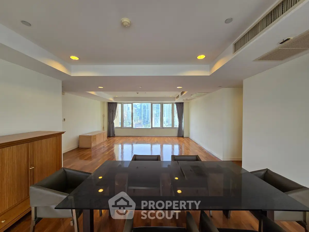 Spacious modern living room with city view, featuring elegant dining area and hardwood floors.
