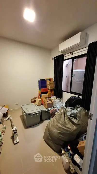 Compact storage room with window and air conditioning, ideal for organizing household items.