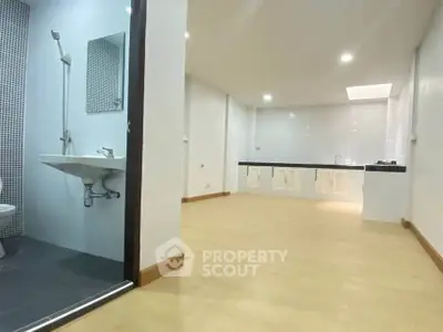 Spacious open-plan living area with adjacent modern bathroom and sleek kitchen.