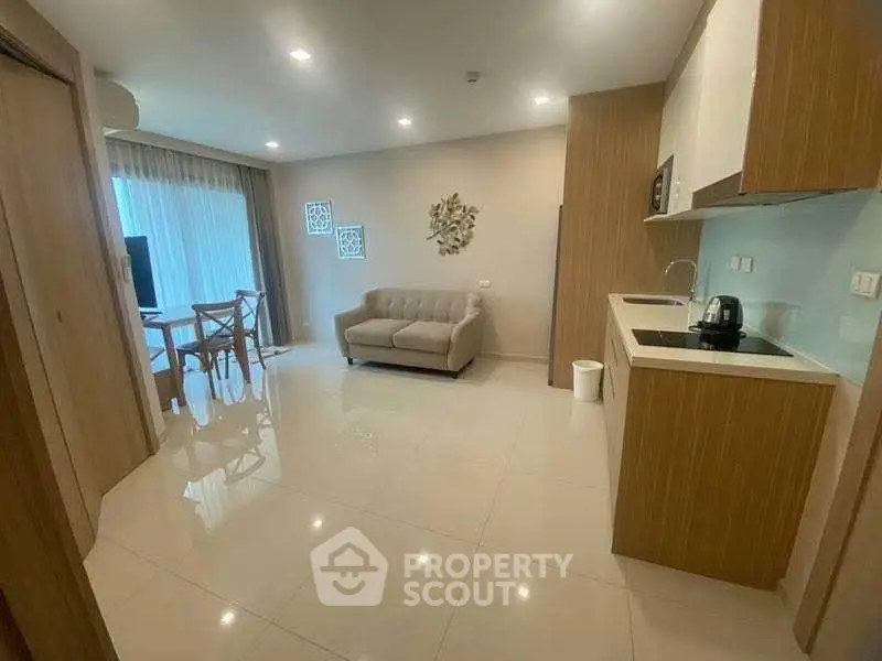 Modern open-layout living room with kitchen, featuring sleek design and natural light.