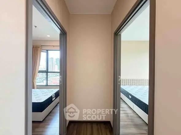 Modern apartment with two bedrooms and city view, featuring wooden flooring and large windows.