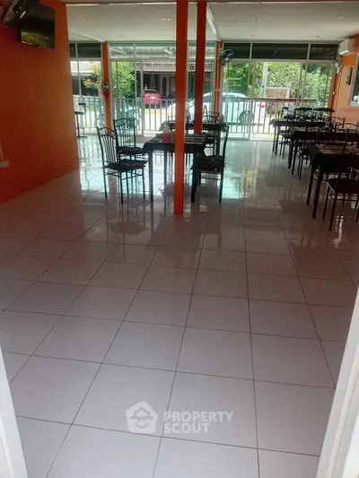 Spacious dining area with tiled flooring and ample natural light, perfect for a restaurant or cafe setup.