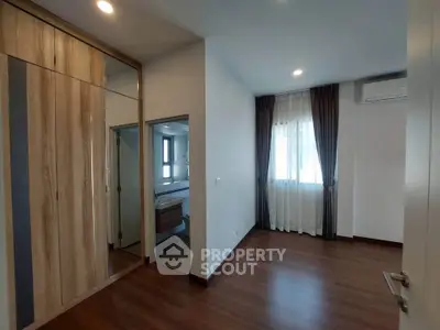 Spacious bedroom with wooden flooring and large window in modern apartment