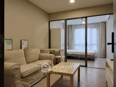 Modern living room with cozy sofa and glass partition leading to bedroom