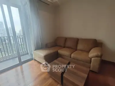 Cozy living room with brown sofa and wooden coffee table, featuring a city view from the balcony.