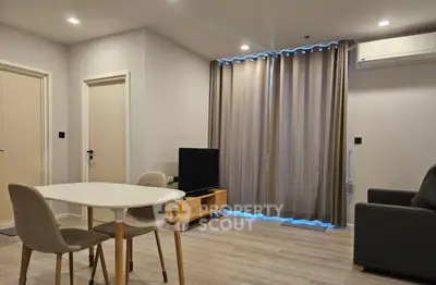 Modern living room with sleek furniture and large window draped with curtains, featuring a minimalist design.