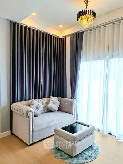 Elegant living room with plush sofa, chic chandelier, and floor-to-ceiling curtains.