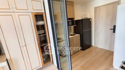 Modern compact kitchen with sleek cabinets and appliances in a cozy apartment setting.