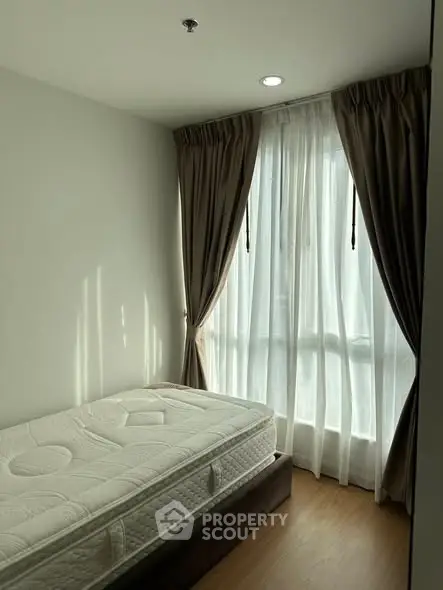 Cozy bedroom with natural light and elegant curtains, featuring a comfortable mattress.