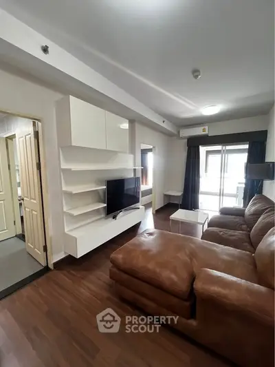 Modern living room with brown leather sofa and wall-mounted TV in a stylish apartment.