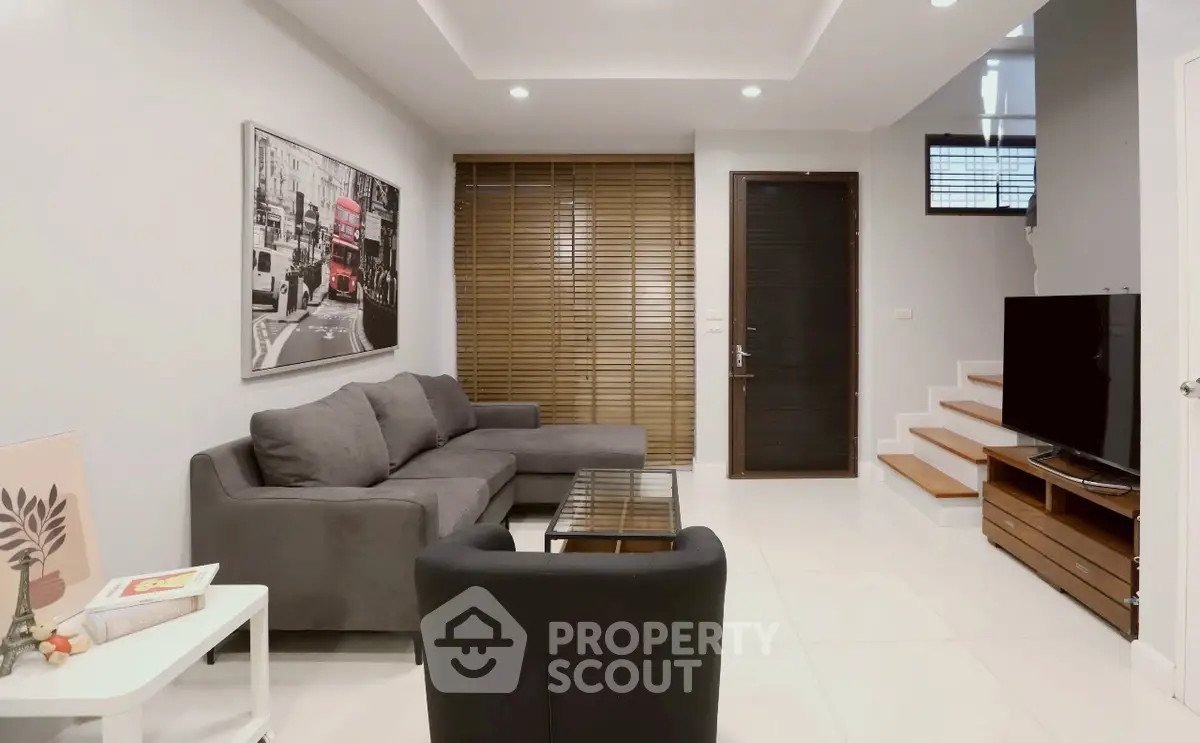 Modern living room with stylish furniture and natural light, featuring a cozy gray sofa and sleek decor.