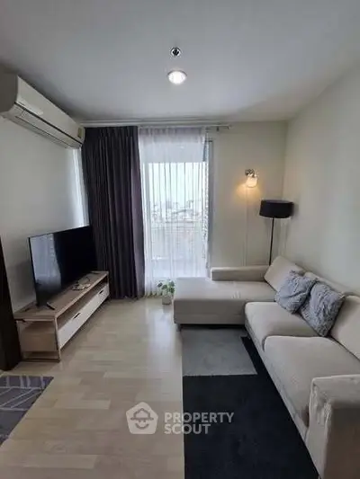 Modern living room with sleek furniture and large window offering city view.