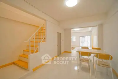 Spacious modern living area with dining table and staircase, featuring bright natural lighting.