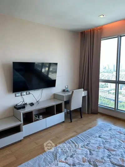 Modern bedroom with city view, featuring a wall-mounted TV and a cozy workspace.
