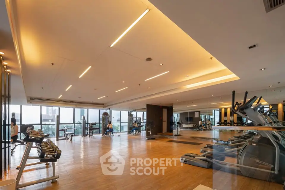 Spacious modern gym with panoramic windows and state-of-the-art equipment in luxury residential building.