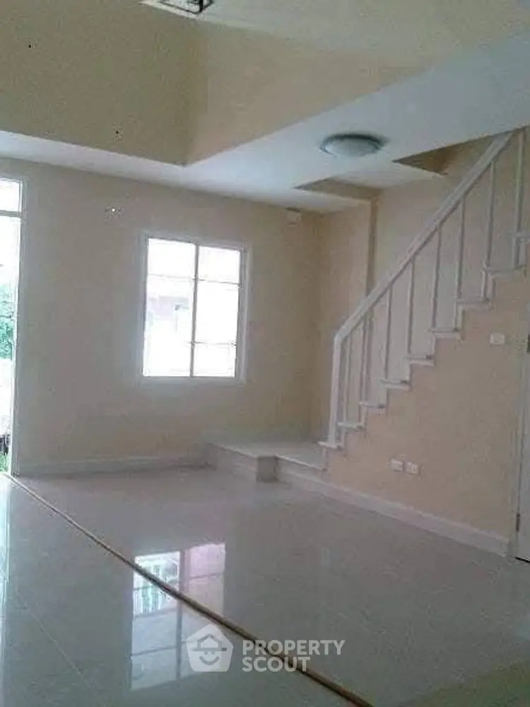 Spacious living room with modern staircase and natural light