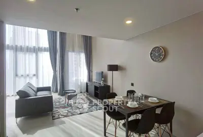 Modern living room with dining area, stylish furniture, and large windows for natural light.