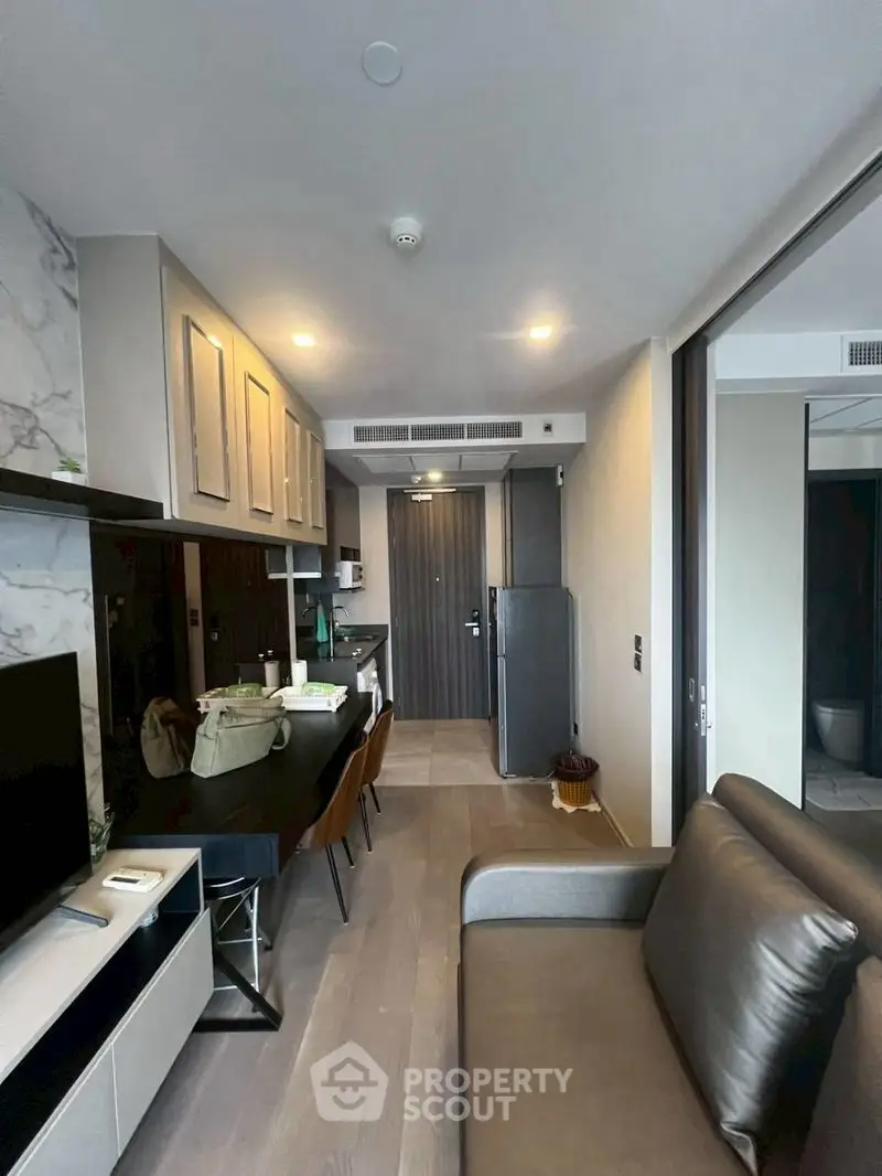 Modern apartment interior with open kitchen and cozy living area, featuring sleek design and contemporary furnishings.
