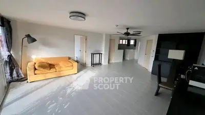 Spacious living room with modern decor and ample natural light, featuring a cozy yellow sofa and sleek tile flooring.