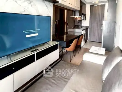 Modern living room with sleek TV, open kitchen, and stylish furniture in a contemporary apartment.