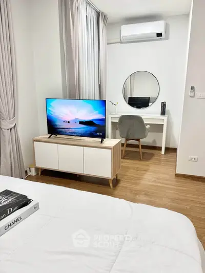 Modern bedroom with stylish decor, featuring a TV, desk, and air conditioning.