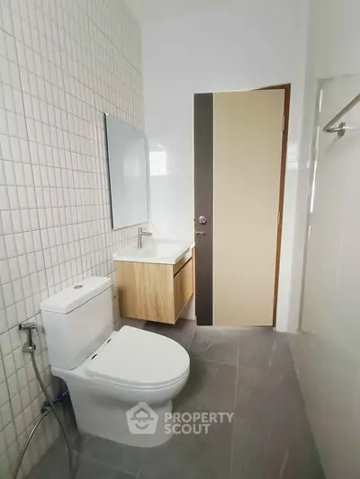 Modern bathroom with sleek fixtures and minimalist design, featuring a wall-mounted sink and tiled walls.