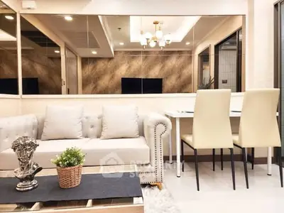 Elegant living room with plush sofa and dining area, featuring modern decor and ambient lighting.