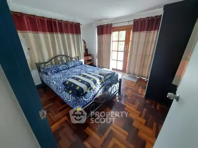 Cozy bedroom with stylish parquet flooring and natural light through large windows.