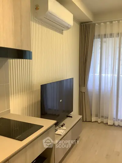 Modern living room with sleek TV, air conditioning, and elegant curtains in a stylish apartment.