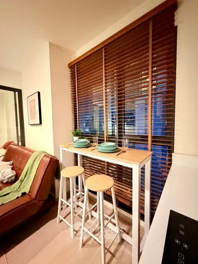 Chic modern living room with stylish bar seating and large window blinds.