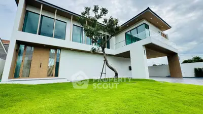 Modern two-story house with large windows and lush green lawn, showcasing contemporary architecture and spacious design.