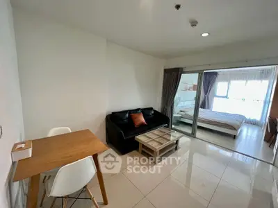 Modern apartment with open living room and bedroom, featuring sleek furniture and ample natural light.