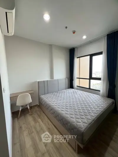 Modern bedroom with large window and stylish furnishings in a high-rise apartment.