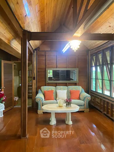 Charming wooden living room with cozy sofa and large windows offering natural light.