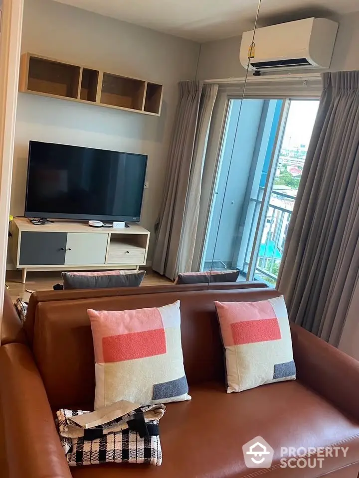 Modern living room with brown leather sofa, TV, and balcony view in stylish apartment.