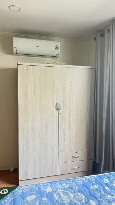 Cozy bedroom with air conditioning and wooden wardrobe, perfect for comfortable living.