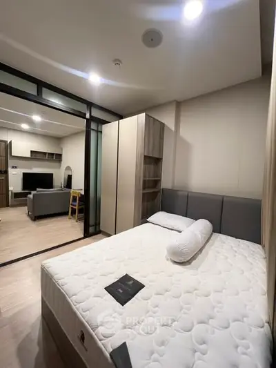 Modern bedroom with stylish decor and view into a cozy living room, perfect for urban living.
