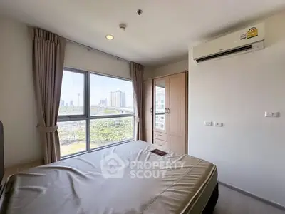 Bright bedroom with large window and city view, featuring air conditioning and wardrobe.