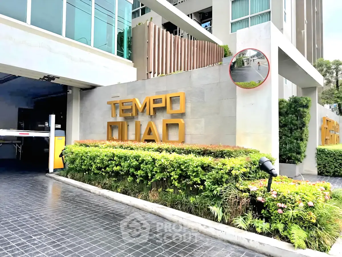 Modern building entrance with lush greenery and stylish signage