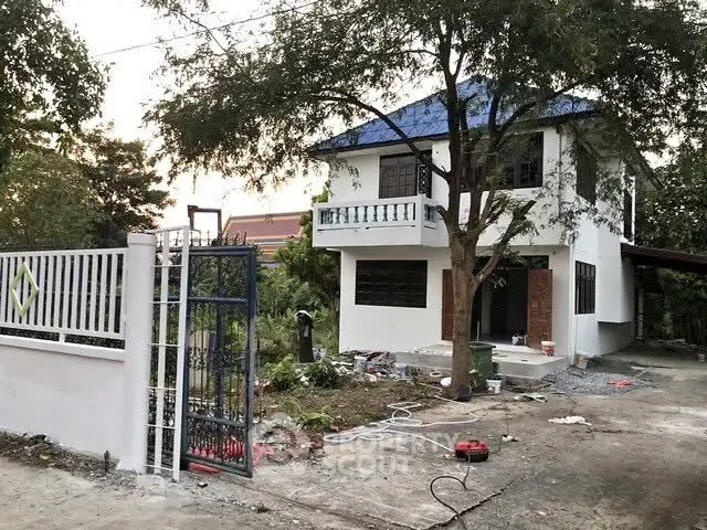 Charming two-story house with blue roof and spacious driveway in a serene neighborhood.