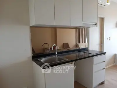 Modern kitchen with sleek white cabinetry and black countertop, featuring a built-in sink and ample storage space, perfect for culinary enthusiasts.