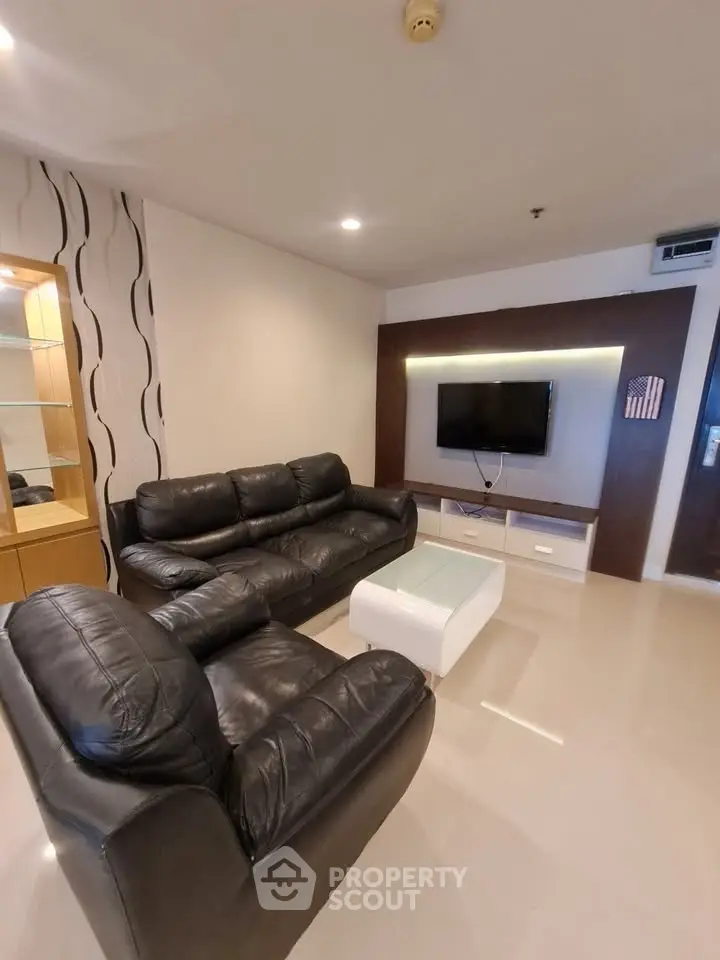 Modern living room with sleek leather sofas and wall-mounted TV in a stylish apartment.