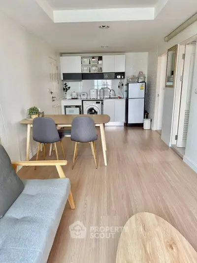 Modern open-plan living room with kitchen, featuring stylish furniture and appliances, ideal for urban living.