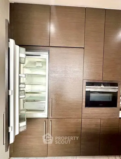 Modern kitchen with built-in fridge and oven in sleek wooden cabinetry.