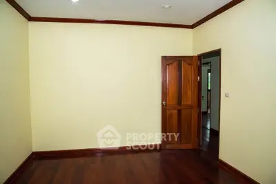 Spacious empty room with wooden flooring and door, ideal for customization.
